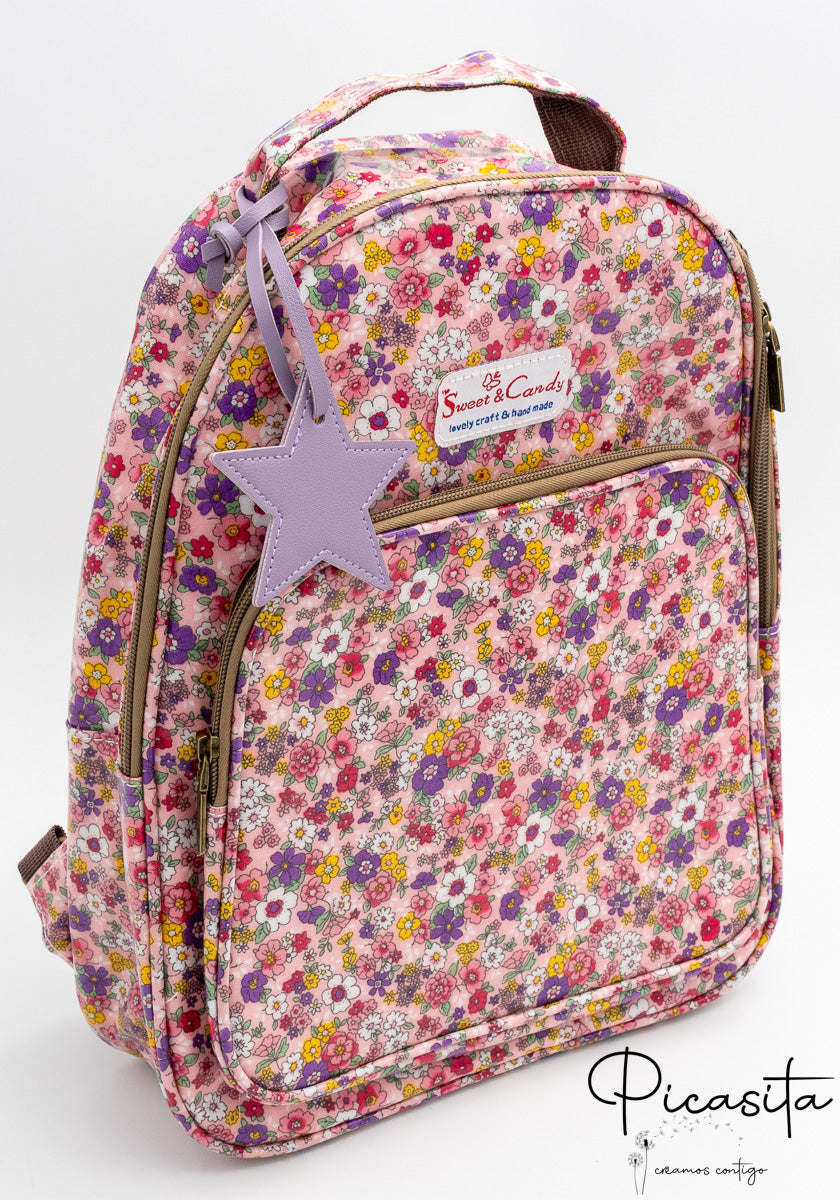 Mochila escolar con estampado de flores rosas y lilas con charm de estrella morada.