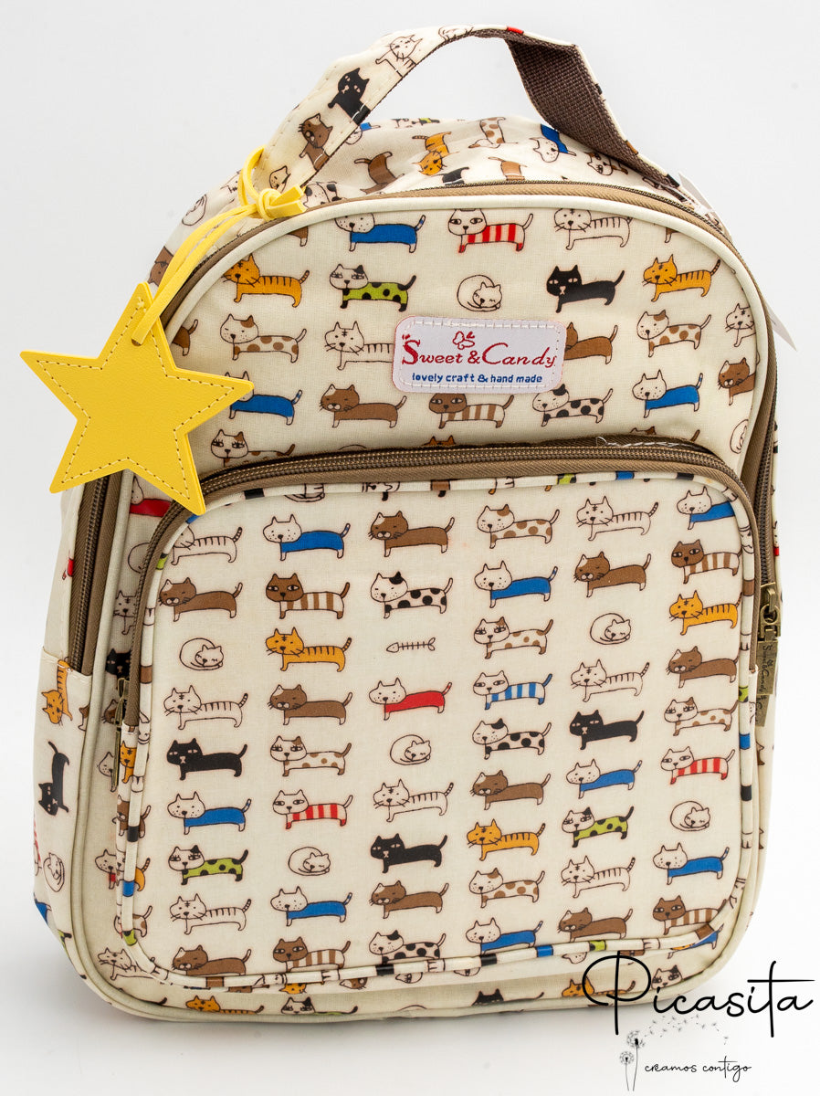 Mochila color crema con patrón de gatos de colores y charm amarillo colgante.