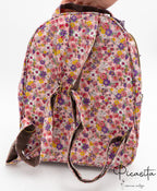 Parte posterior de la mochila con correas ajustables y asa superior de color marrón.
