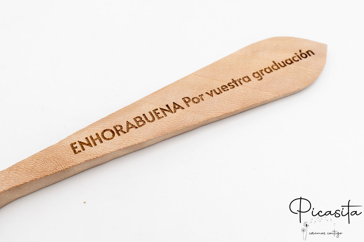 Detalle macro del mensaje de enhorabuena grabado sobre el veteado natural de la madera.