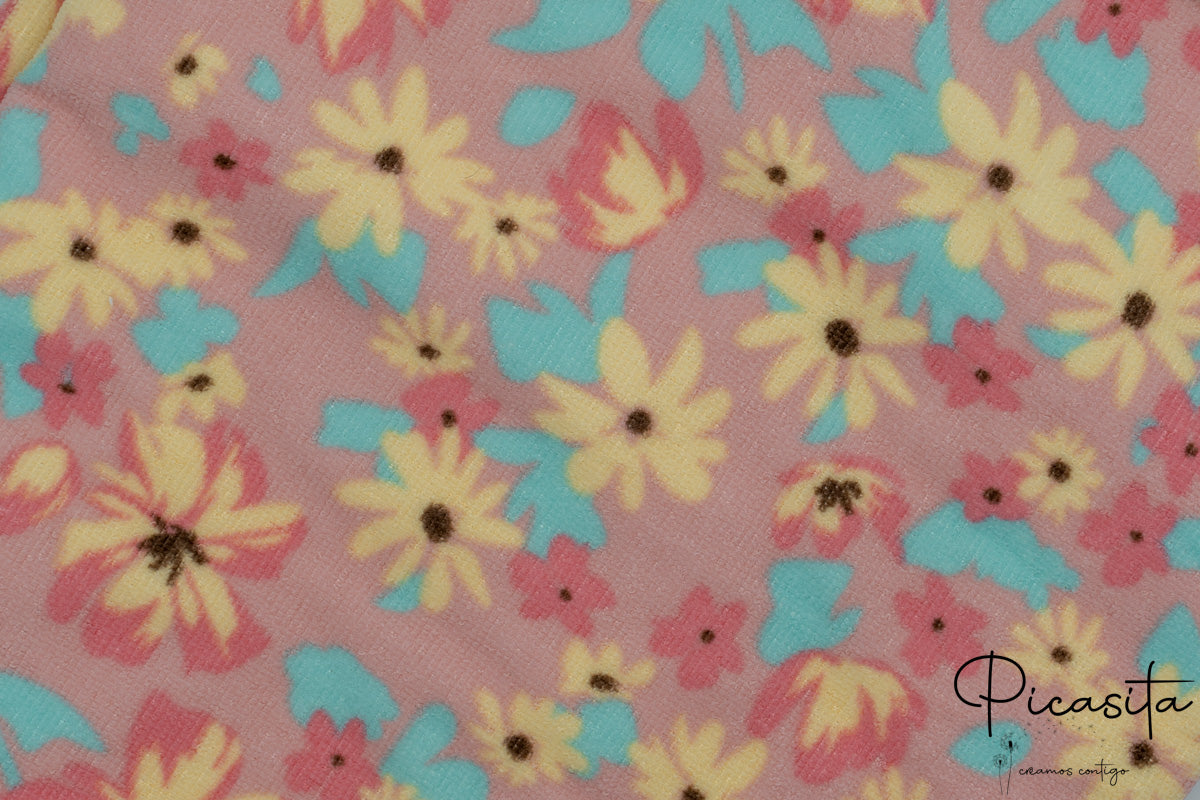 Detalle de tejido de toalla rosa con estampado floral de margaritas amarillas y azules.