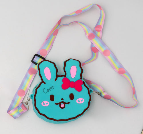 Bolso de silicona azul con forma de conejo, lazo rojo y cinta arcoíris.