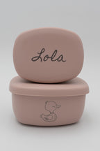 Dos tuppers rosa apilados con el nombre Lola y dibujo de pato