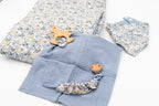 Blaues Set mit geblümter Decke, Halstuch-Lätzchen, blauem Musselintuch mit Schaukelpferd-Beißring aus Holz und Schnullerkette mit Holzclip.