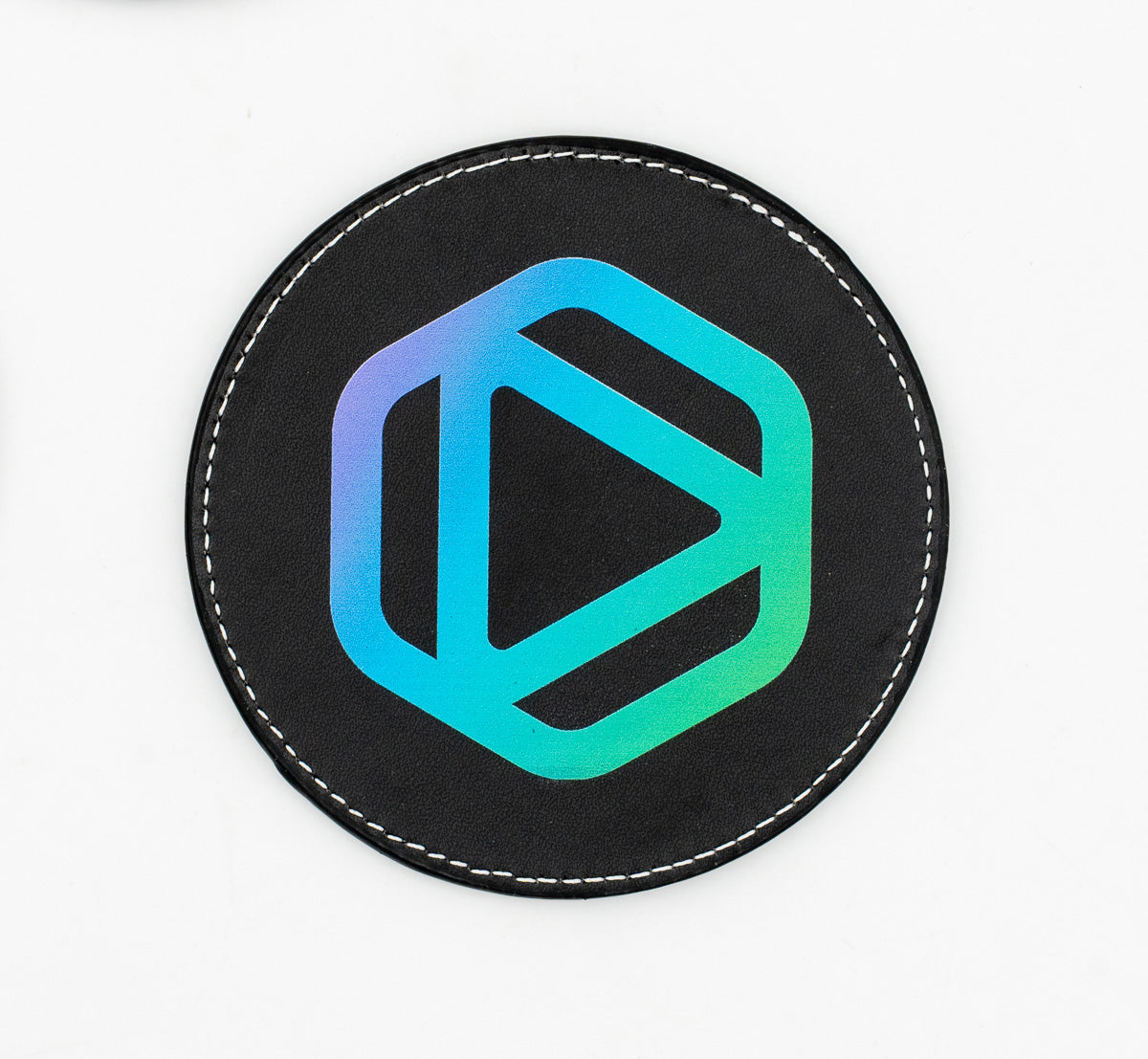 Runder schwarzer Untersetzer mit blauem und grünem geometrischem Emblem.