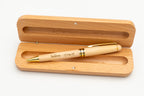 Offenes Etui mit hellem Holz-Kugelschreiber mit Kappe und goldfarbenen Details.