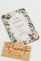 Hochzeitseinladung aus Holz mit Eukalyptusblättern und Rosen in den Ecken