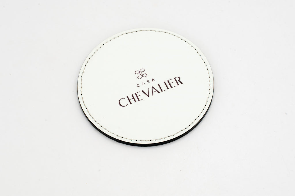 Runder weißer Untersetzer mit grauem Chevalier-Logo.