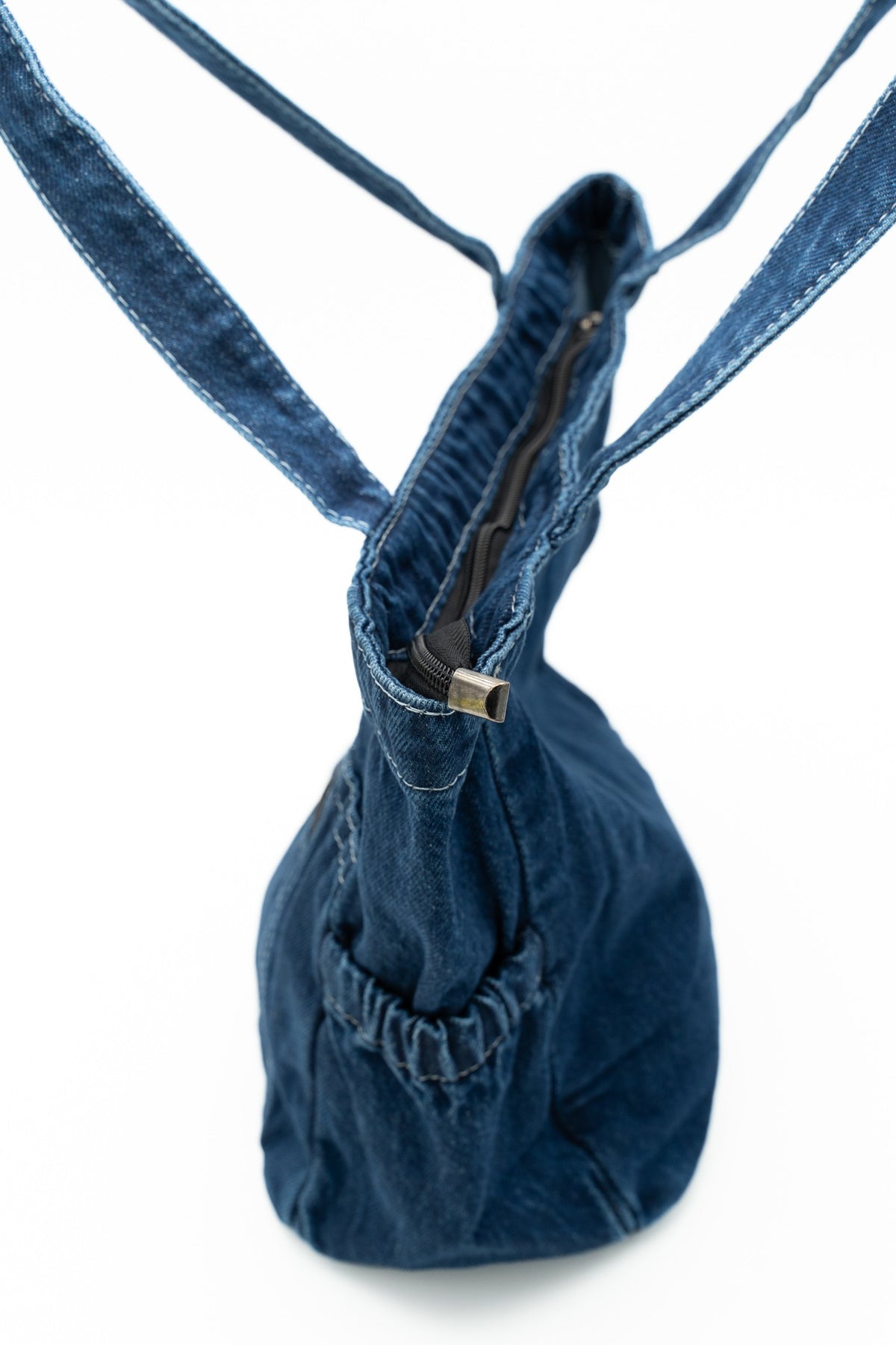 Seitenansicht einer Jeanstasche mit oberem Reißverschluss und geraffter Seitentasche