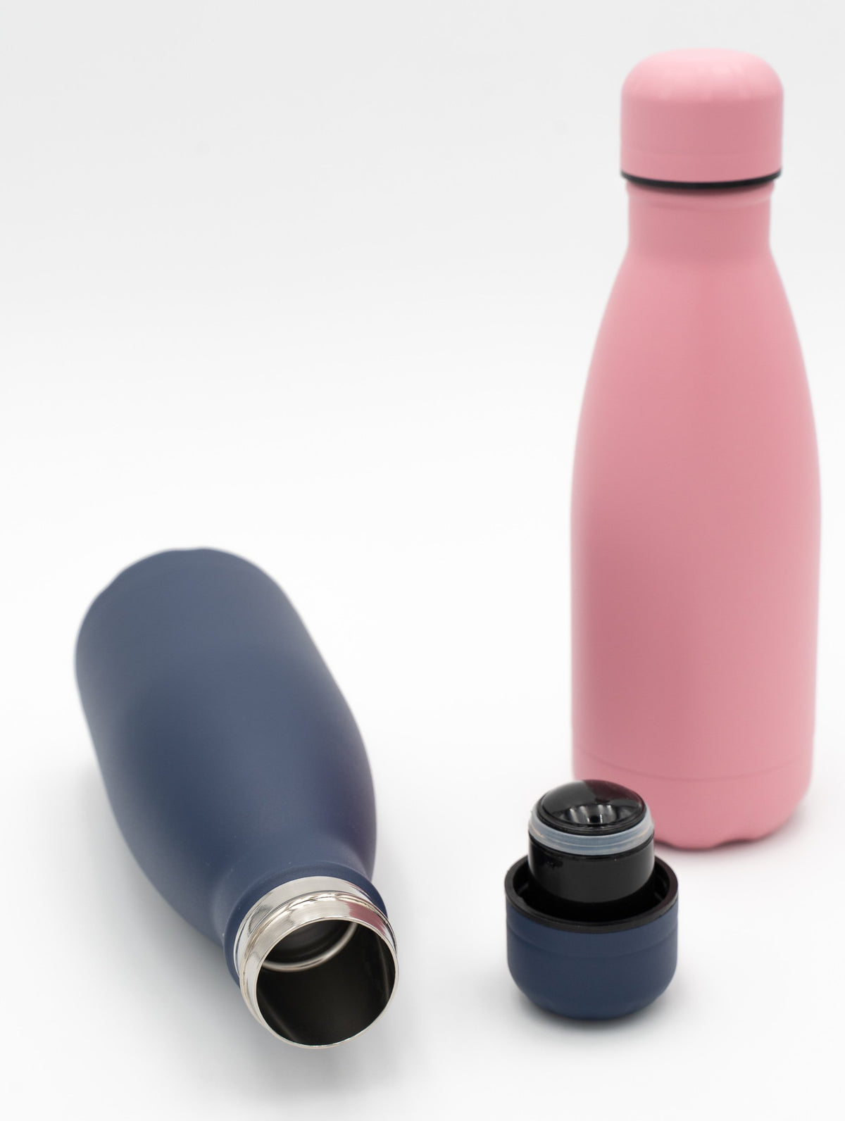 Marineblaue und rosa Thermosflaschen, eine geöffnet neben ihrem Schraubverschluss