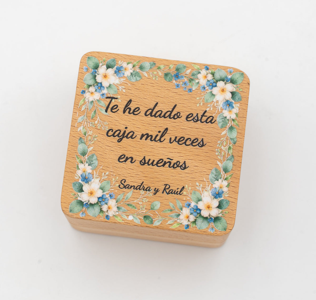 Quadratische Ringbox aus Buche mit farbig bedruckten blauen Blumen und dem Satz «Te he dado esta caja mil veces en sueños»