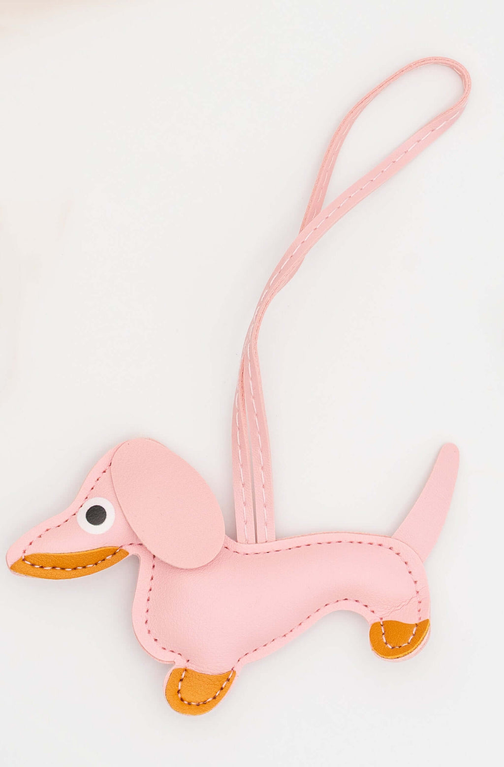 Figura de perro salchicha en polipiel rosa claro con cordón de sujeción a juego.