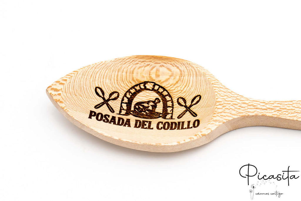 Primer plano de grabado láser detallado con motivos de cocina sobre madera clara pulida.