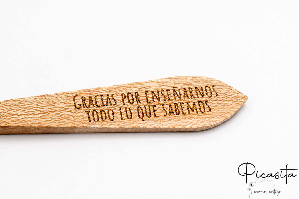 Texto conmemorativo grabado con precisión láser en la superficie plana del mango de madera.