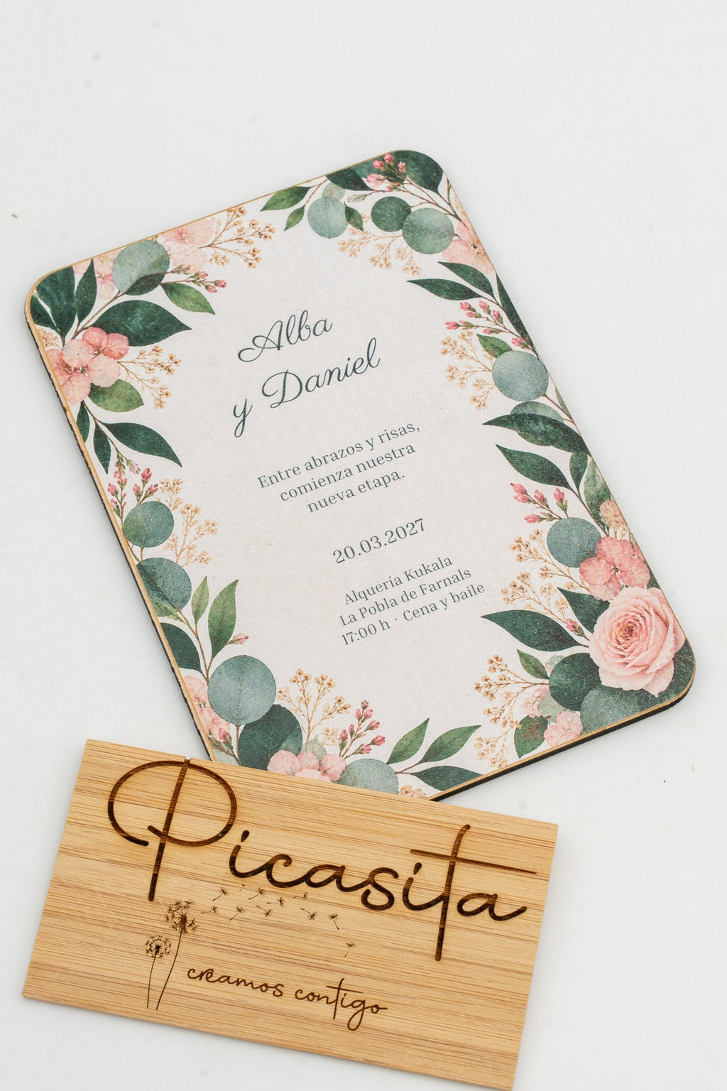 Hochzeitseinladung aus Holz mit Eukalyptusblättern und Rosen in den Ecken