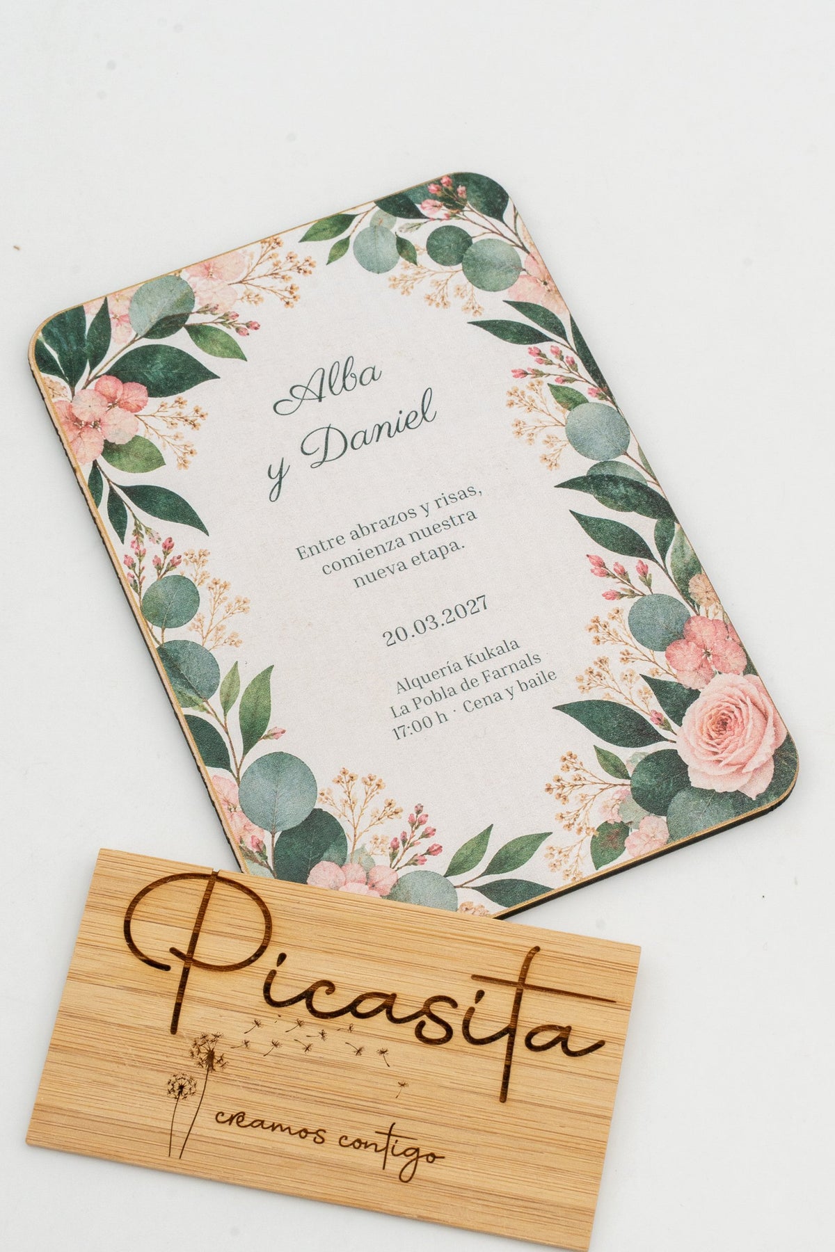 Hochzeitseinladung aus Holz mit Eukalyptusblättern und Rosen in den Ecken