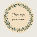 Digitale Vorschau: rundes Schild mit Eukalyptus und Blumen, dem Text „Papá, aquí viene mamá“ und zwei oberen Löchern.