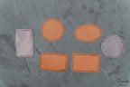 Conjunto de parches personalizados en diferentes formas geométricas sobre una superficie de piedra gris.