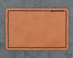 Parche rectangular de polipiel con esquinas redondeadas y costura decorativa negra perimetral.