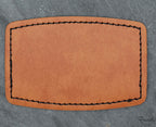Parche de polipiel con forma rectangular y laterales curvados con detalle de costura negra.