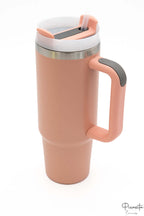 Vaso térmico color salmón con asa y tapa con detalle en gris oscuro.