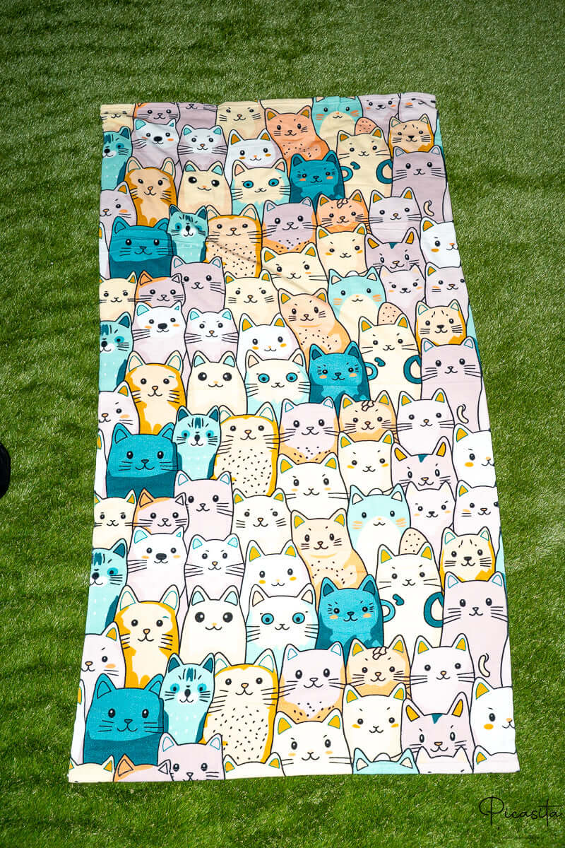 Toalla con estampado de gatitos coloridos incluyendo tonos turquesa y amarillo.